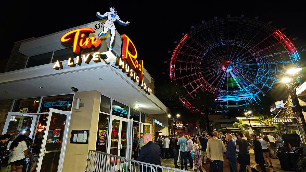 people around exterior of Tin Roof Orlando with ferris wheel in background in Orlando, Florida, USA